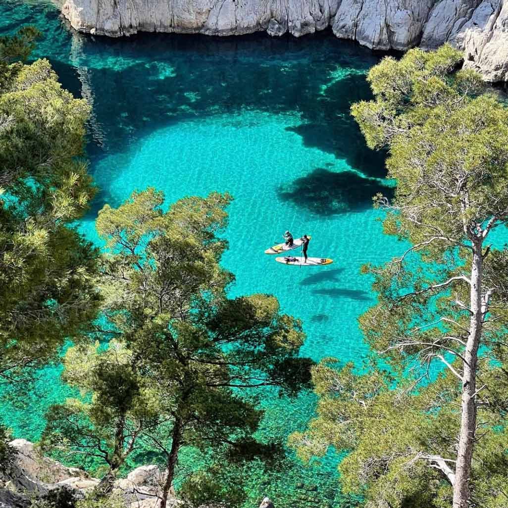 Deux personnes en stand-up paddle sur l'eau turquoise translucide d'En-Vau.