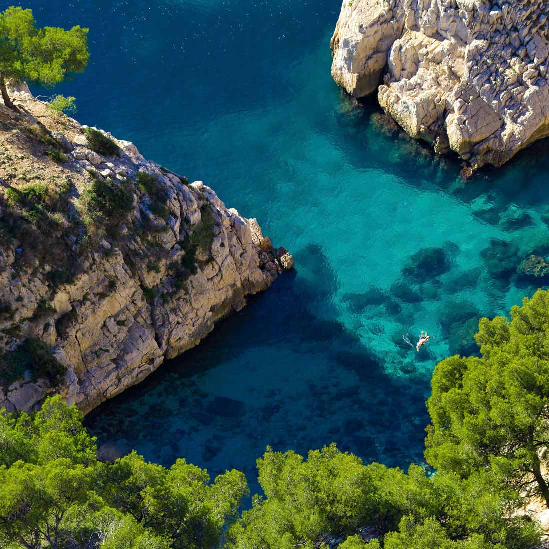 Vue aérienne plongeante sur un nageur solitaire dans les eaux turquoise de Sugiton.