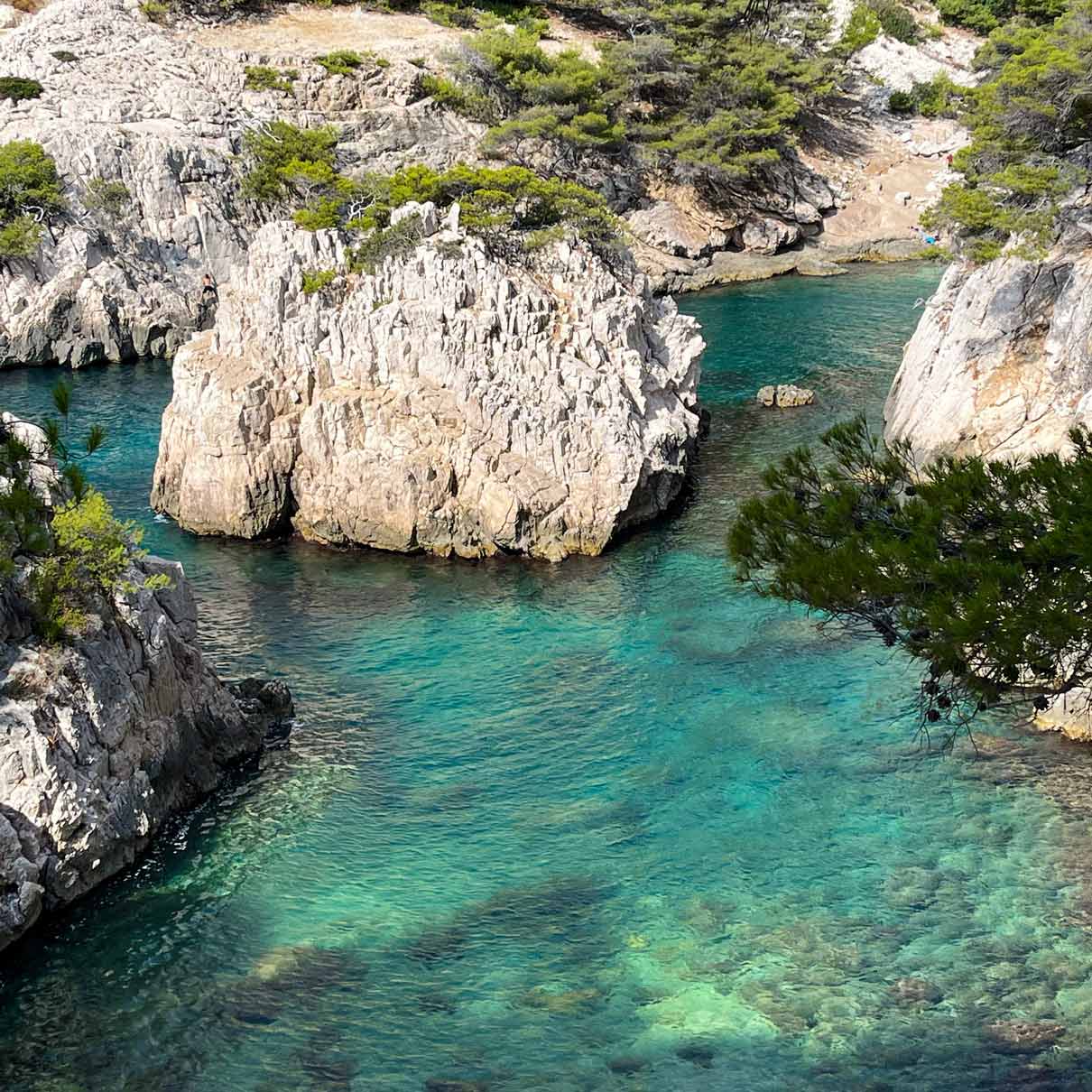 Gros plan sur l'îlot rocheux de Sugiton entouré d'une eau translucide.