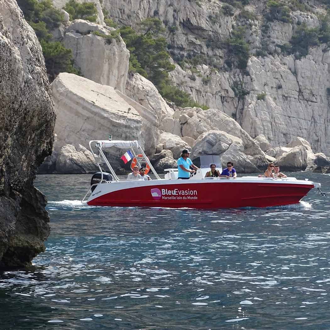 Bateau de Bleu Évasion transportant des passagers devant les falaises de Sugiton.