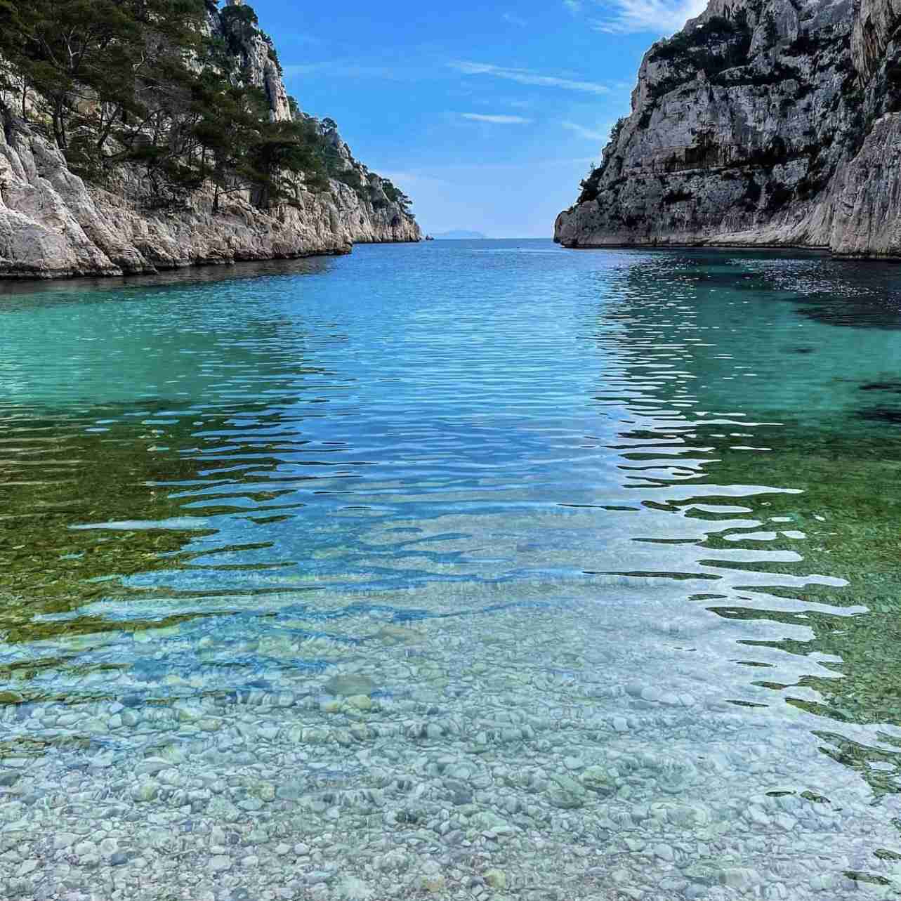 Hautes falaises de calcaire blanc surplombant les eaux turquoise de la calanque d'En-Vau.